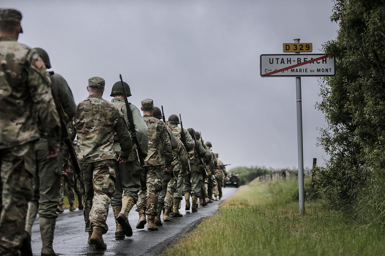Karybos entuziastai ir JAV kariai keliauja link Normandijos paplūdimio, kuriame 1944 m. išsilaipino sąjungininkai