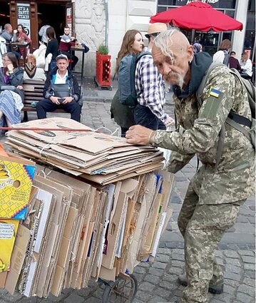 Kaip kazokas atrodantis ukrainietis renka makulatūrą ir iš to suduria galus.