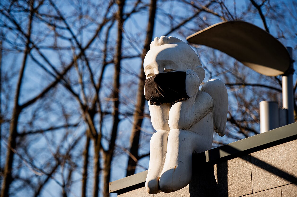 Ant URM pastato nutūpęs angeliukas su apsaugine kauke