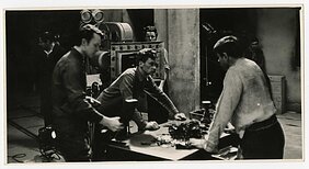 Vaidybinio filmo „Niekas nenorėjo mirti“ (rež. Vytautas Žalakevičius, Lietuvos kino studija, 1965 m.) filmavimas.  Pirmame plane antras iš kairės operatorius Jonas Gricius.  Pirmame plane trečias iš kairės aktorius Donatas Banionis.