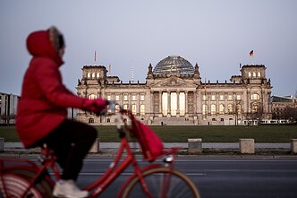 A woman rides past the Reichstag building, the seat of the German Bundestag in Berlin.