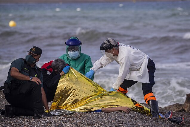Medikai apžiūri kūną migranto, kuris mirė galimai bandydamas apiplaukti Ispanijos anklavo sieną 2021-ųjų gegužės mėnesį.