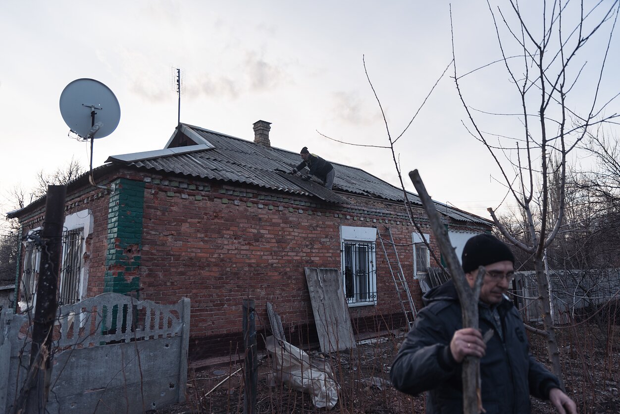 People in the village of Pivniche, in eastern Ukraine, clear up the rubble after an artillery strike destroyed a civilian house