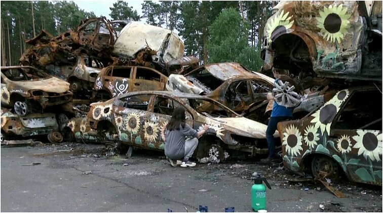 Kare sudeginti automobiliai tapo Ukrainos menininkų drobe: ant nuolaužų tapomos saulėgrąžos