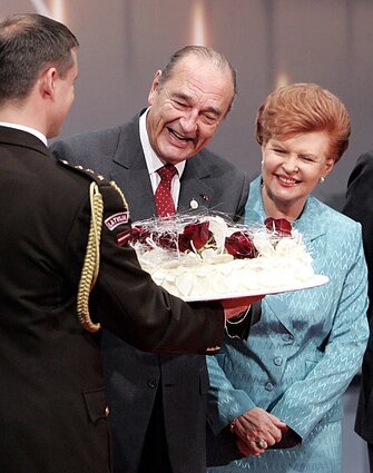 Latvian President Vaira Vīķe-Freiberga gifts a birthday cake to French President Jacques Chirac at the NATO summit in Riga