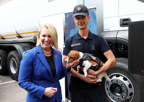 Šuniukas Patronas ir jo šeimininkas Mykhailo Ilyevas pozuoja nuotraukai su JAV ambasadore Ukrainoje Bridget Brink.