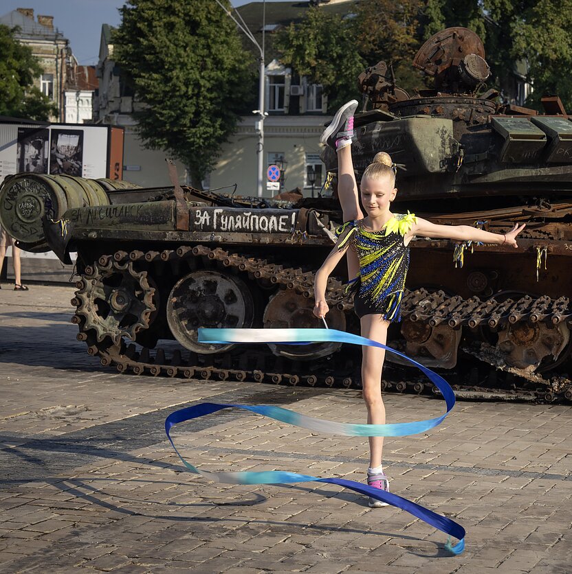 AP  nuotr., Kijeve mergina koncertuoja šalia sunaikintų Rusijos karinių transporto priemonių