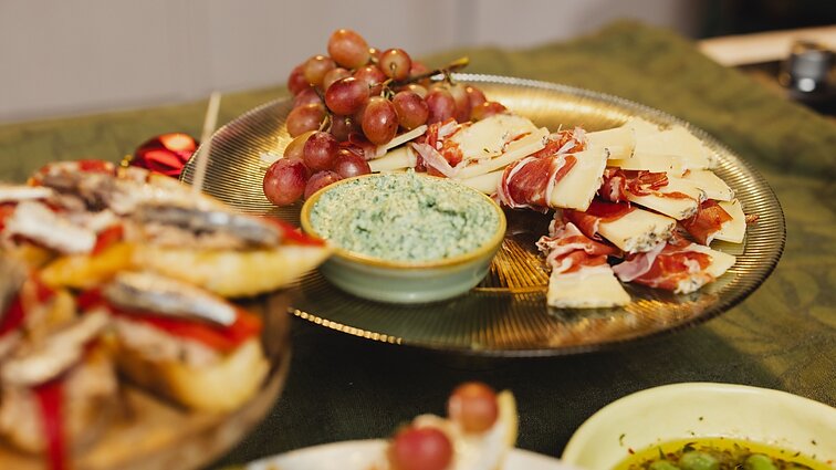 Užkandžių stalas ispaniškai: pinčo su keptomis vynuogėmis, mančego sūris su kumpiu bei artišokų ir rikotos užtepėlė