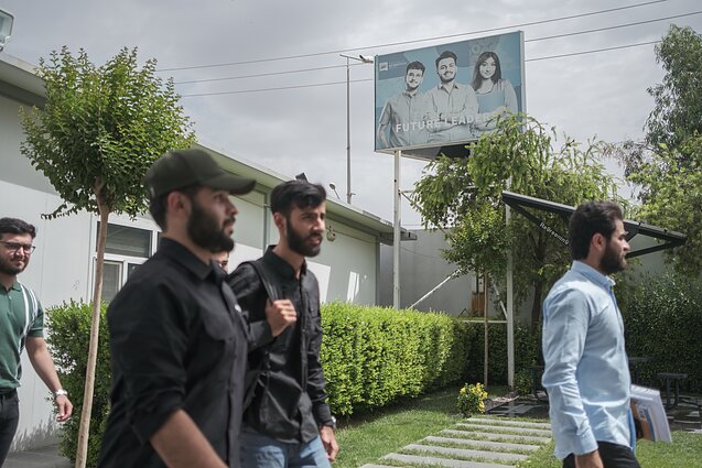 Universiteto studentai eina pro išblukusį reklaminį stendą „Ateities lyderiai“. Universiteto studentai eina pro išblukusį reklaminį stendą „Ateities lyderiai“.