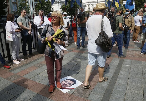 Protestuotoja užlipo ant plakato su Volodymyro Zelenskio veidu