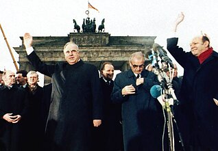 На этом фото от 22 декабря 1989 года канцлер Западной Германии Гельмут Коль (слева) вместе с премьер-министром Восточной Германии Хансом Модровым (второй справа) перед Бранденбургскими воротами во время церемонии у Берлинской стены На этом фото от 22 декабря 1989 года канцлер Западной Германии Гельмут Коль (слева) вместе с премьер-министром Восточной Германии Хансом Модровым (второй справа) перед Бранденбургскими воротами во время церемонии у Берлинской стены