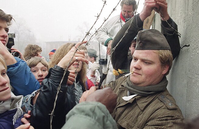 Rytų Vokietijos pasienietis rodo spygliuotos vielos gabalus, kuriuos nupjovė nuo Berlyno sienos, 1989 m. lapkričio 14 d. Rytų Vokietijos pasienietis rodo spygliuotos vielos gabalus, kuriuos nupjovė nuo Berlyno sienos, 1989 m. lapkričio 14 d.