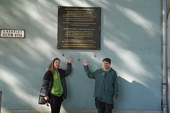 Aistė and Augustinas with a memorial plaque for Paulius Normantas in Hungary