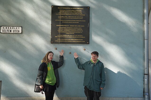 Aistė and Augustinas with a memorial plaque for Paulius Normantas in Hungary