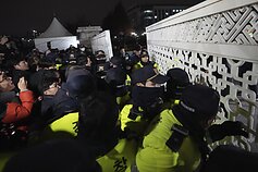 Policijos pareigūnams budint prie Nacionalinės Asamblėjos Seule, žmonės bando patekti į vidų