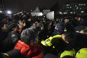 Policijos pareigūnams budint prie Nacionalinės Asamblėjos Seule, žmonės bando patekti į vidų