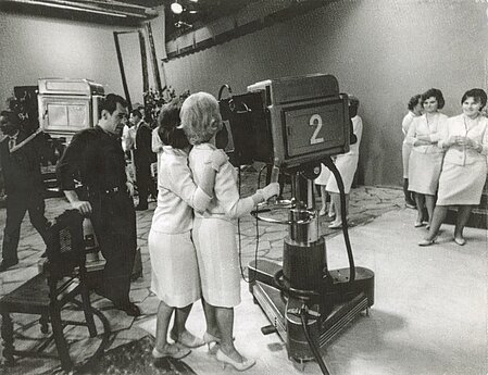 Besiruošiant muzikinės laidos filmavimui. Studijoje prie filmavimo kameros operatorius Gintautas Dabkus. 1965 m.  