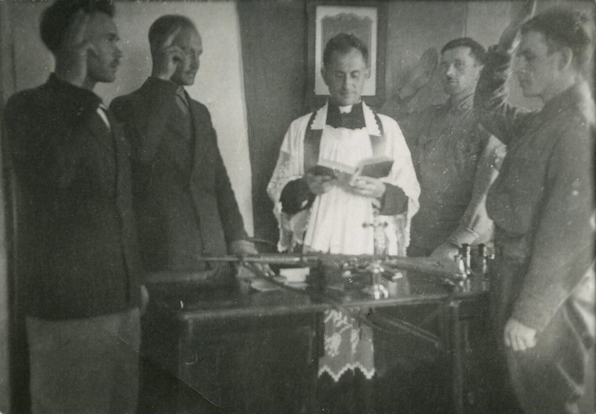 Pirmojo Tauro apygardos štabo pareigūnų priesaika. Skardupių klebonija (Marijampolės vlsč.), 1945 m. liepos 19 d. Iš kairės stovi: Jonas Pileckis-Brokas, apygardos vadas Leonas Taunys-Kovas, apygardos kapelionas Antanas Ylius-Vilkas, Albinas Ratkelis-Oželis ir Vytauto rinktinės vadas Vytautas (Vitalius) Gavėnas-Vampyras Pirmojo Tauro apygardos štabo pareigūnų priesaika. Skardupių klebonija (Marijampolės vlsč.), 1945 m. liepos 19 d. Iš kairės stovi: Jonas Pileckis-Brokas, apygardos vadas Leonas Taunys-Kovas, apygardos kapelionas Antanas Ylius-Vilkas, Albinas Ratkelis-Oželis ir Vytauto rinktinės vadas Vytautas (Vitalius) Gavėnas-Vampyras