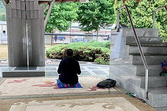 Apžiūrėjęs Srebrenicos memorialą, turistas atsiklaupia pasimelsti