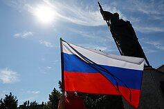 Rusijos „Junarmijos“ karinio patriotinio judėjimo narys mojuoja Rusijos vėliava per memorialinį renginį, skirtą nuo 2014 m. Donbase žuvusiems vaikams, Bohdano Chmelnickio prospekte Rusijos okuopuotame Melitopolyje