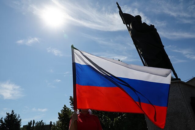 Rusijos „Junarmijos“ karinio patriotinio judėjimo narys mojuoja Rusijos vėliava per memorialinį renginį, skirtą nuo 2014 m. Donbase žuvusiems vaikams, Bohdano Chmelnickio prospekte Rusijos okuopuotame Melitopolyje