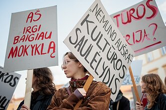Demonstrators holding signs reading “Nemunas Dawn – the Dusk of Culture” and “I Too Finished School.”