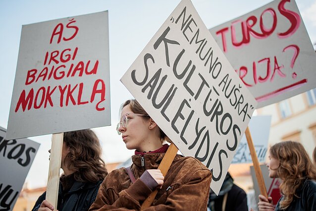 Demonstrators holding signs reading “Nemunas Dawn – the Dusk of Culture” and “I Too Finished School.”