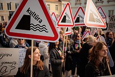 Protesters displaying placards depicting culture being thrown over the hill