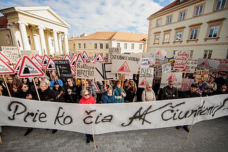 Protestors hold a sign reading “What does M. K. Čiurlionis have to do with this?” pointing to Adomavičius' lack of experience