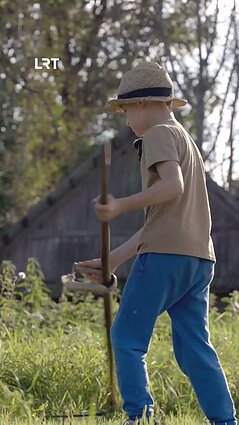 Treiderių šeimynos atžala demonstruoja, kaip dalgiu šienauti žolę