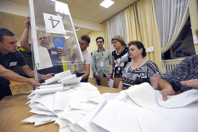 Члени місцевої виборчої комісії виймають бюлетені для підрахунку голосів на виборчій дільниці після голосування на позачергових виборах народних депутатів України, Київ, 21 липня 2019 року.