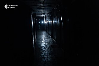 The long common corridor of the former dormitory is lit only by flashlights on phones.