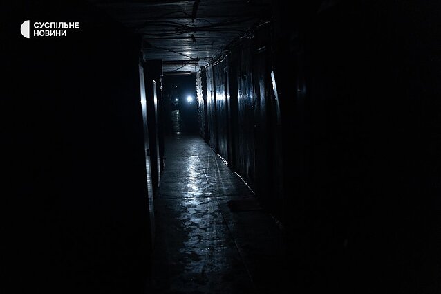 The long common corridor of the former dormitory is lit only by flashlights on phones.