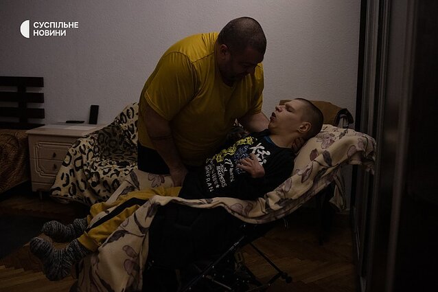 Taras transfers his son Bohdan, who has a severe form of cerebral palsy, from his bed to a wheelchair. Bohdan's life depends on the people around him.