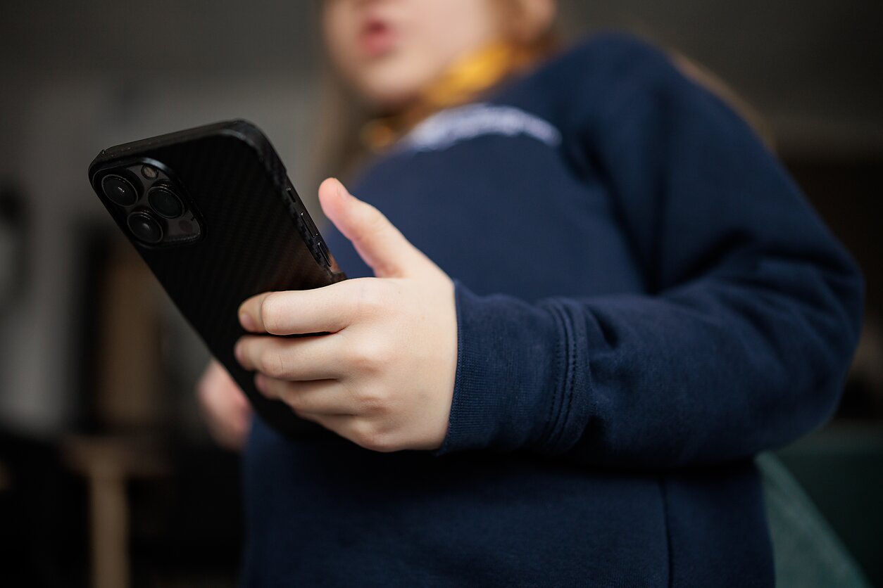 Vaikas su mobiliu telefonu