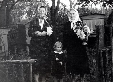Erna Enzinaitė su jurginus laikančiomis Barbike ir Evike Enzinaitėmis prie savo namų Karklininkuose.  20 a. 7 deš.
