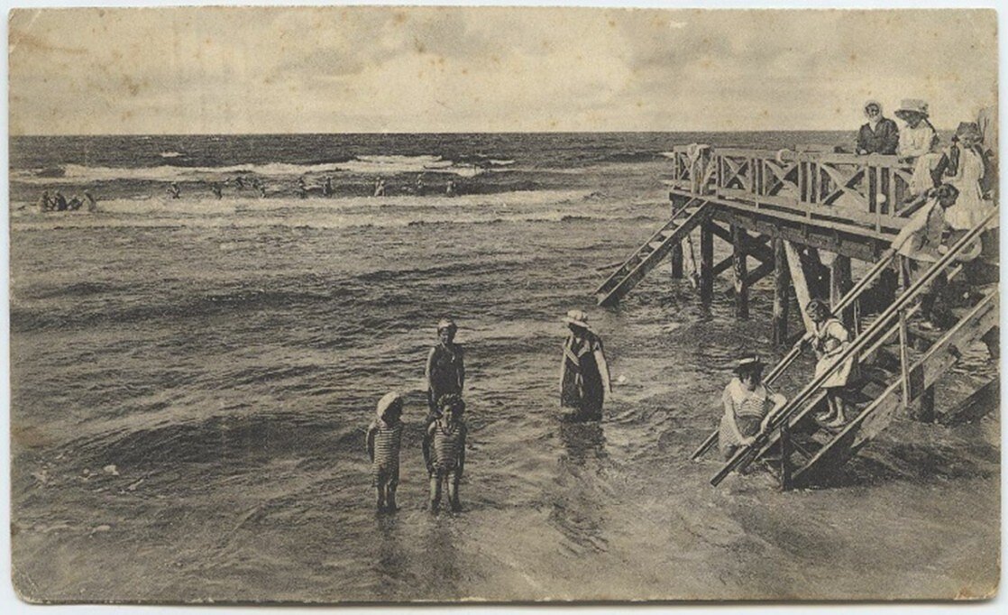 Moterys ir vaikai maudosi prie Palangos jūros tilto, 1905 m. Damos dėvi maudymosi sukneles ir skrybėles, o vaikai – uždarus maudymosi kostiumus. Paulinos Mongirdaitės atvirukas. Moterys ir vaikai maudosi prie Palangos jūros tilto, 1905 m. Damos dėvi maudymosi sukneles ir skrybėles, o vaikai – uždarus maudymosi kostiumus. Paulinos Mongirdaitės atvirukas.