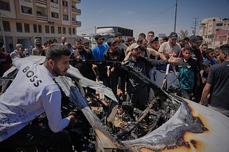 Palestiniečiai Gazos Ruože apžiūri automobilį, į kūrį smogė Izraelis
