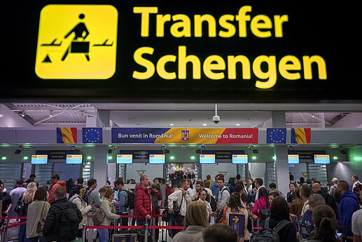 Pasażerowie przybywający na międzynarodowe lotnisko im. Henriego Coandy przechodzą pod tablicą informacyjną strefy Schengen w Otopeni, niedaleko Bukaresztu